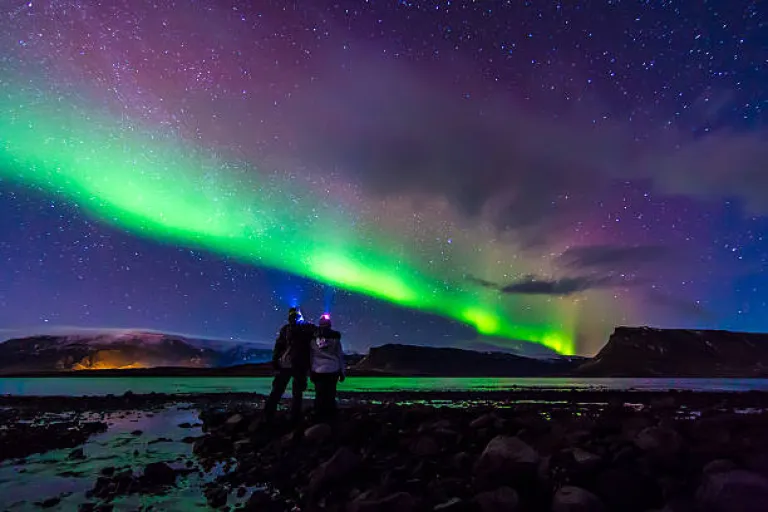 Young Couple hugged under Northern lights Aurora Borealis in Iceland