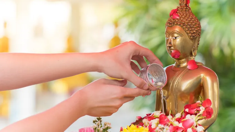 Traditional pouring of water over a Buddha statue