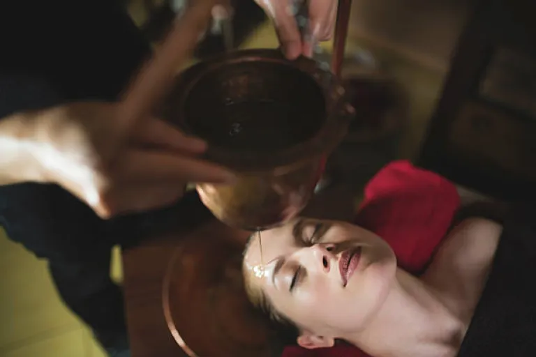 Young woman having an ayurvedic shirodhara treatment in Kerala.