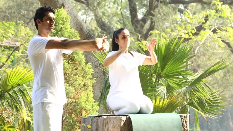 Instructor teaching yoga pose to woman