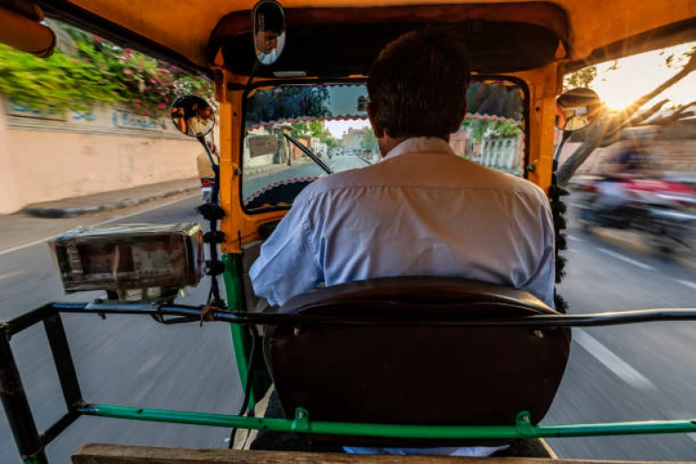 Indian man drives auto rickshaw (tuk-tuk) on streets of Rajasthan, India.