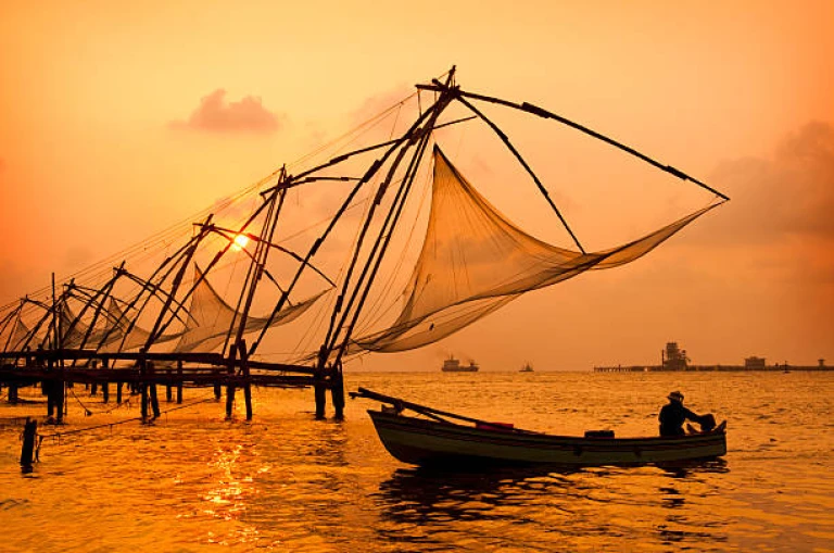 A sunset over Chinese fishing nets by a canoe in Cochin