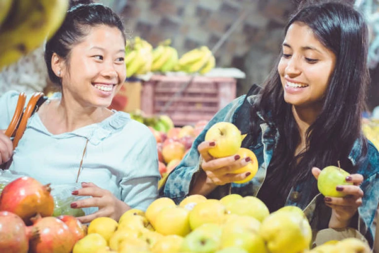 Women buying fruit at street shop