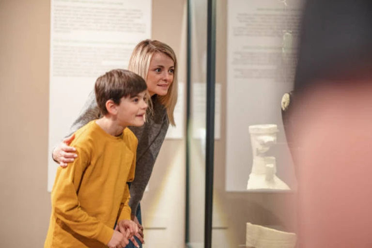 Enthusiastic Young Boy Looking At The Artifacts While Visiting A Museum With His Family